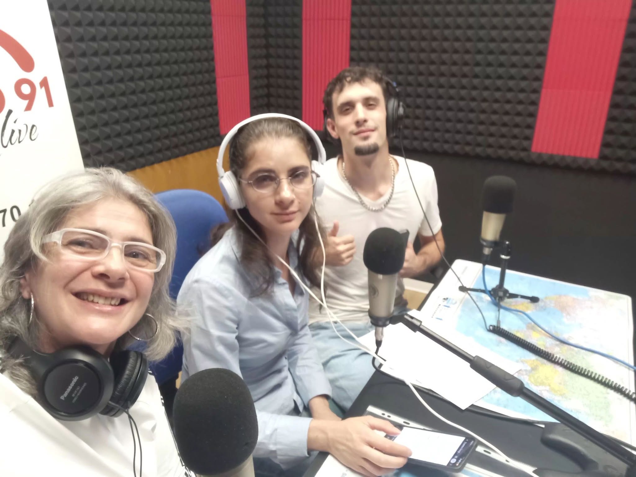 Tre organizzatori del festival con le cuffie, seduti davanti ai microfoni nello studio di Radio Studio 91 Live