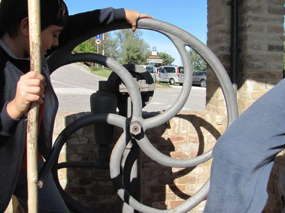 Bambini azionano la ruota della pompa del pozzo